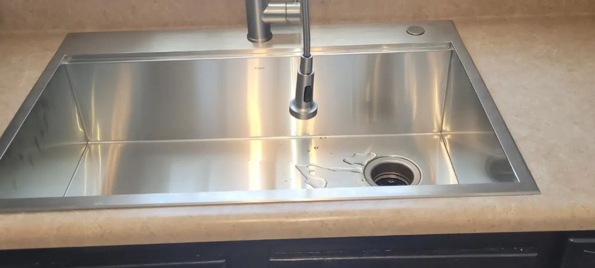 The same counter after: a deep stainless single-bowl sink with a tall spring faucet.