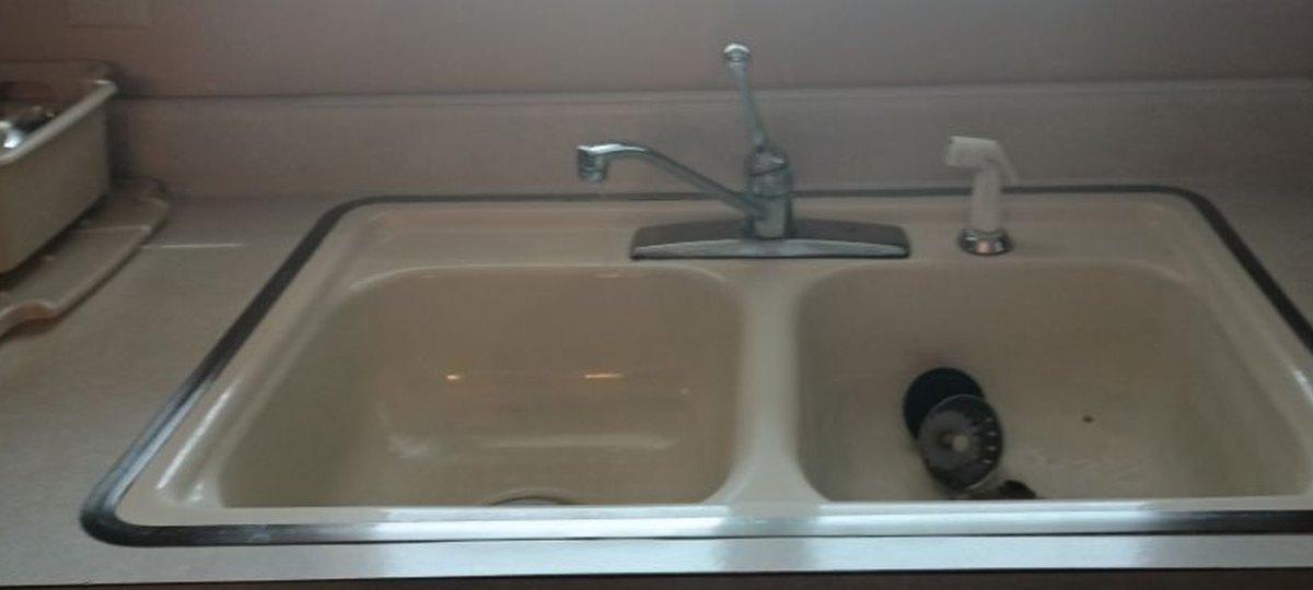 The kitchen before: an almond drop-in double sink with a chrome faucet, set in a beige counter.