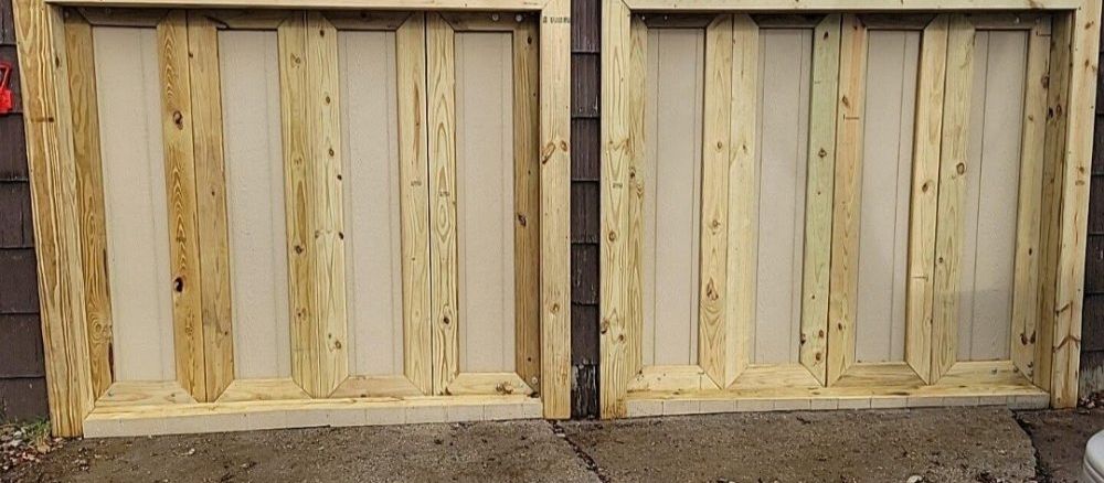 New pressure-treated timber framing built in two square bays, standing on bare ground outside.